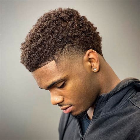 Medium length temple fade. 9. Cool Temple Fade. Today’s black men haircuts are anything but boring. This clean look is the perfect combination of retro and modern. For this style, don’t get the back cut to the skin. Instead, leave it at a medium length for a faux hawk effect. An afro fade is a style that always exudes creativity. 
