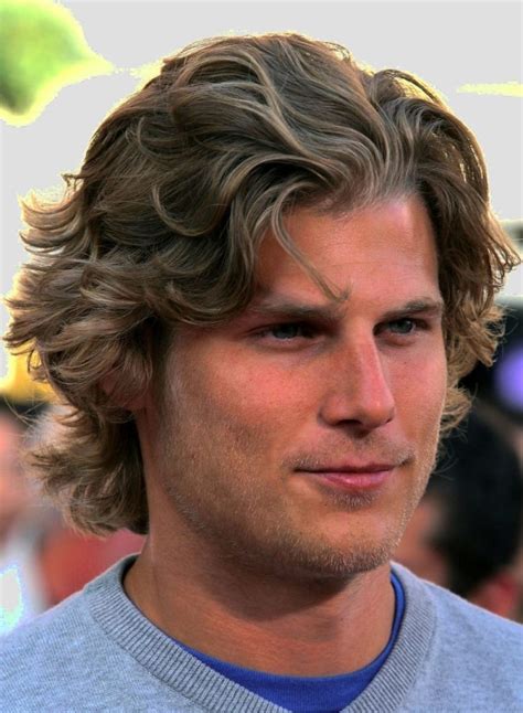 Mens wavy hairstyles. This man's long, straight hair channels a classic rock 'n roll aesthetic, flowing freely past his shoulders. The natural chestnut hue enhances the depth of his locks, complementing his serene expression. This style is best for men with straight or slightly wavy hair who prefer laid-back yet striking looks. 