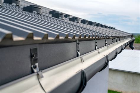 Metal roof gutters. Rain will slide off the roof quickly and the gutters need to be strong enough to catch the rainfall. Keep size in mind. The size of the gutter system on a metal roof depends on the climate, how big the roof is, and its pitch. Usually, the panels should overhang the gutters from 1 to 1.5 inches, but that should be confirmed by a roofing ... 