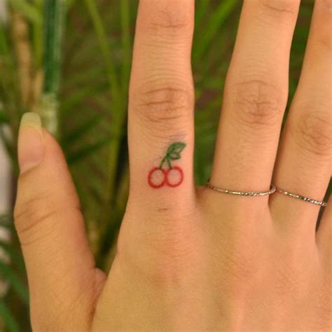 Minimalist cherry tattoo on the finger.
