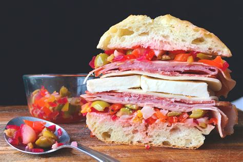 Muffuletta sandwich in new orleans. Divide the bread lengthwise. Scoop out some of the dough-y interior and reserve for another use. Combine the olives, oil, pickled vegetables, red peppers, parsley, vinegar, garlic and Italian ... 