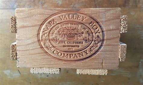 Napa valley box company. Napa Wooden Box Company Wood Slat Box Crate Made in CALIFORNIA by the NAPA WOODEN BOX COMPANY Rustic style Design: Tom Cat Made of wood slats One end of each box has a sticker with a design. The other end of each box has an oval logo imprinted with: NAPA VALLEY BOX COMPANY 