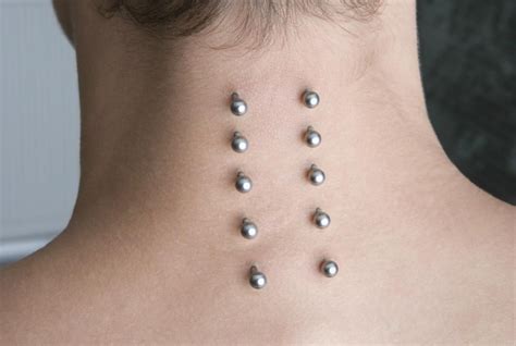 Nape piercing. Nape piercings are a type of surface piercing that's done on the back of the neck. The piercing features two puncture holes with a bar running under the skin. Learn about application,... 