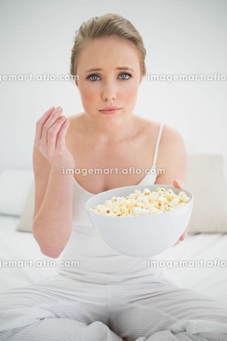 Natural Frowning Blonde Holding Bowl Of Popcorn On Bed In …