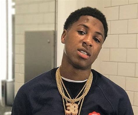 13) Graphic-Print Excellence. NBA Youngboy makes a statement with a bold graphic-print t-shirt. He pairs it with ripped jeans and high-top sneakers, creating an eye-catching, trendy outfit. The graphic element adds a touch of personality and individuality to his look. Image Via Pinterest.