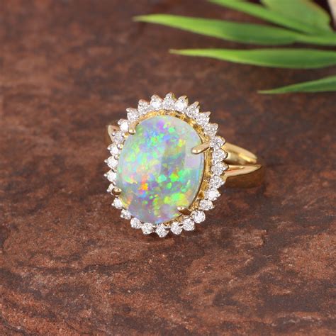 Opal and diamond ring. Enchanting from the inside, this oval-shaped opal and diamond ring brings fairytale sparkle to daily style. One oval-shaped opal gemstone in a halo of sixteen round brilliant cut diamonds offers deep scintillation beyond compare. 
