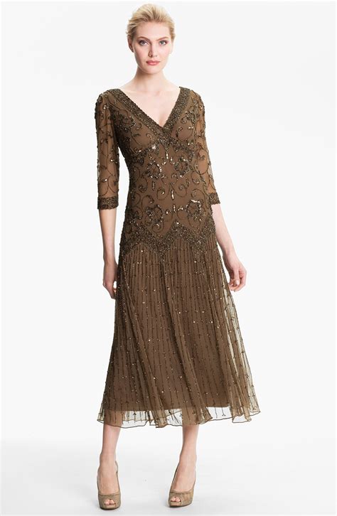 The Pisarro Nights Embellished Mesh Gown is a mother of the bride dress that has an embroidered and embellished mesh overlay to create a glamorous effect. The bodice features lace-up detailing, zipper closure at back, and delicate cap sleeves with matching eyelet trim.. 