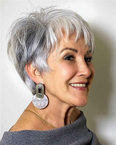 1. Feathered Pixie Haircut. This platinum blonde pixie is perfect for women over 60 looking to embrace their gray hair. The feathered fringe is a little longer around the face to add a feminine touch to a short haircut. Don’t forget to use purple shampoo to keep your hair color bright and brass-free. @presleypoe.. 