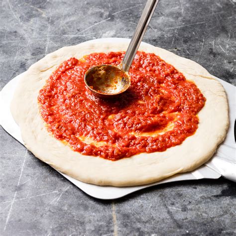 Pizza sauce with tomato. 1. Measure out and prepare all of the ingredients. 2. Slice the fresh garlic cloves crosswise in slivers. 3. Pour the canned whole tomatoes into a bowl. Smash the tomatoes with your hands to create bits. 4. Add olive oil to a frying pan over medium heat. 