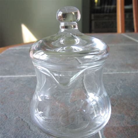 This beautiful Princess House Heritage footed candy jar with lid is a stunning addition to your collection. The round, crystal clear jar is etched with a classic Heritage pattern, adding a touch of elegance to any room. Crafted from glass, this original candy jar with lid stands at 8 inches tall and features a footed design.. 