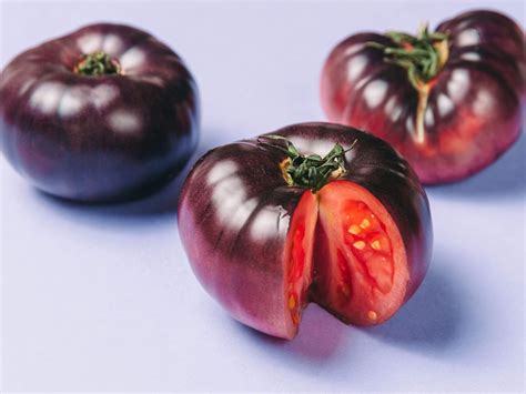 Purple tomato. 14. Rosella Tomato. The Rosella Tomato is a purple cherry-type tomato. These minuscule tomatoes are found in clusters and are ideal for snacking or culinary usage. The sweetness and acidity of the flavor are nicely balanced. Gourmet Genetics, a firm known for producing delicious tomatoes, developed the Rosella Tomato. 