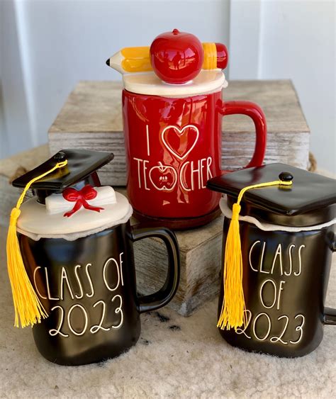 Shop Home's Rae Dunn White Brown Size OS Coffee & Tea Accessories at a discounted price at Poshmark. Description: This is a Brand New 2 pk. Graduation Mugs with lids. These are glazed ceramic with graphic print. Measurements: ️ Brand New ️5"H X 3 3/4"W 🛍 Bundle & Save! 0591. Sold by ckcloset1. Fast delivery, full service customer support.. 