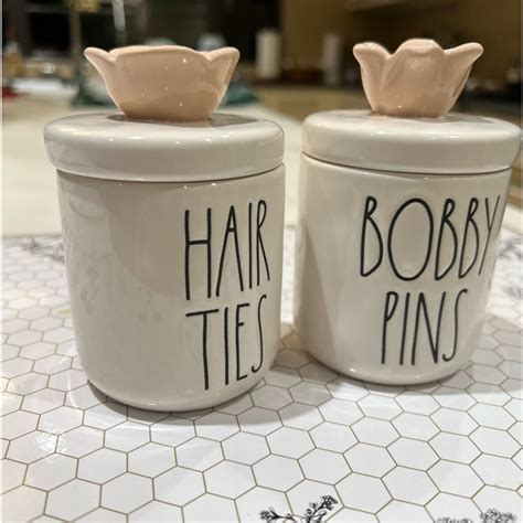 Rae dunn hair ties. New with original packaging Rae Dunn Artisan Collection by Magenta Glossy white ceramic container holder canisters with loop handle lid with black text that reads BOBBY PINS on one and HAIR TIES on... 