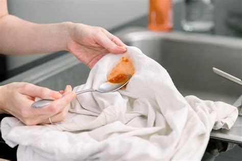 Remove tomato sauce stain. Steps to removing fresh tomato sauce stains. Grab a spoon or a blunt knife and gently scoop some sauce that is scoopable. Make sure to scoop gently so as to not push any more sauce into the fabric. Run or rinse with water, preferably cold. Run water over the back of the stain. 
