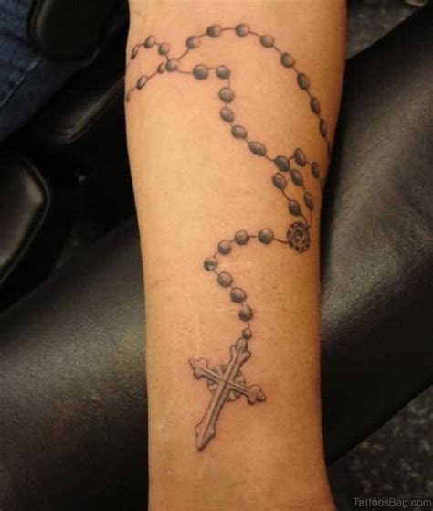 Rosary on arm tattoo. This cross tattoo has an image of roses in the outline of the cross tattoo. Also, the whole cross, along with the roses inside, is given a grey-black ink colour. This neck tattoo can also be done as a leg or arm tattoo design. You might also try sharing some red colours to highlight the roses in the cross tattoo outline. 