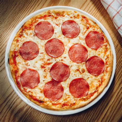 Salami pizza. Place a heavy baking tray or pizza stone into the oven to heat up. Roll one of the dough balls out onto a lightly floured work surface to a 0.5cm/¼in thickness. 