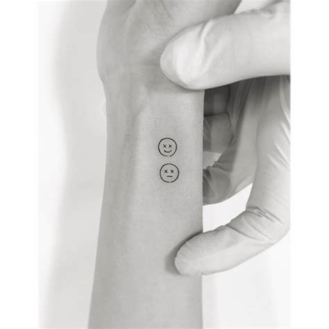 Smiley and sad face tattooed on the wrist.