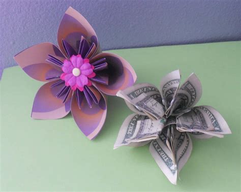 Step by step money origami flower instructions. Take the top corner and fold it down to meet the bottom corner. Then make a crease on the fold. Open the paper back up and repeat this fold with the other end of the paper, folding from left to right. Open the paper back up and rotate it 90 degrees. Now fold the top down on a horizontal fold and crease. 