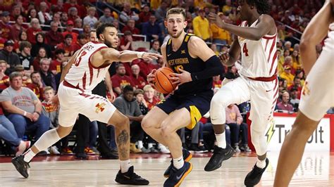 West Virginia guard Erik Stevenson (10) protects the ball from Oklahoma guard Milos Uzan (12) during the first half of an NCAA college basketball game in …