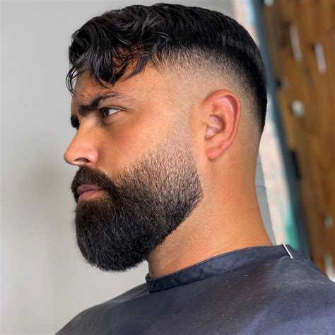 4. Wavy taper fade haircut with beard Wavy Taper Fade Haircut with Beard. The wavy taper fade haircut with a beard is a trendy and stylish look that can be achieved with just a few steps. Here's how: Step 1: Start by washing and towel-drying your hair. Apply some styling products to add texture and volume to your hair.. 