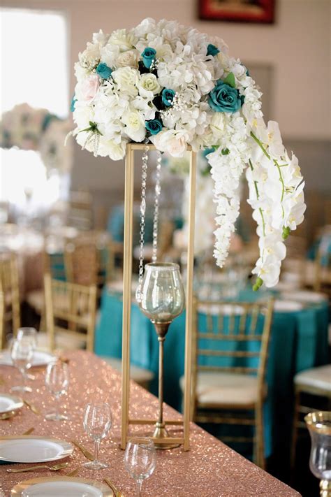 Teal and gold centerpieces. Teal + Gold Wedding Colors Teal is a stunning shade of blue-green that is calming and serene, while gold adds a touch of luxury and opulence. There are many ways to incorporate these colors into your wedding decor, such as using teal and gold table runners, centerpieces with teal flowers and gold accents, or gold candle holders with teal candles. 