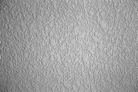 Texture drywall. Knock It Down. After your texture is sprayed on, it needs to set up for about 15 to 30 minutes. It should be tacky but not dry. Drag the knockdown blade lightly across the texture to flatten the tops of the globs of spray. Don't press down too hard—you don't want to actually remove the texture or smear it around. 