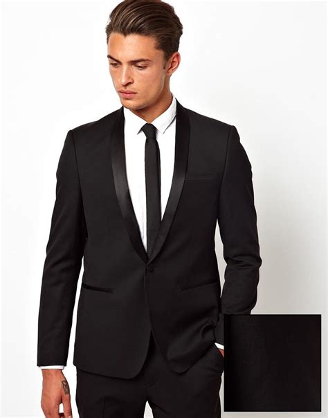 Tuxedo with tie. Tuxedos are worn with bow ties and suits either with or without a tie. Tuxedos have satin lapels, which can even be from a different shade while suits lapels are made of the same fabric. Tuxedos have also satin buttons while suits have the usual suit buttons, not covered by a piece of satin fabric. Tuxedo pants include a satin stripe, while ... 