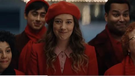 At the center of their ad is a woman in a red hat leading a group of Christmas carolers. She's a prominent figure in the commercial's cast and is played by Kimmy Shields, whom you might recognize ....