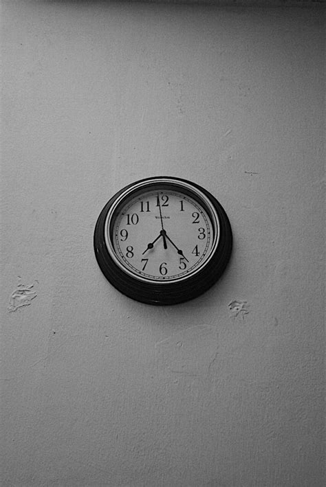 a black and white photo of a clock on the wall of a …