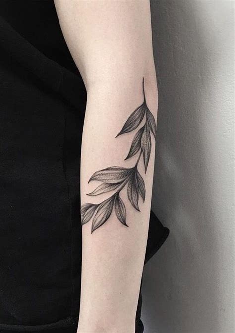 a black and white photo of a leaf tattoo on the left arm, with an arrow