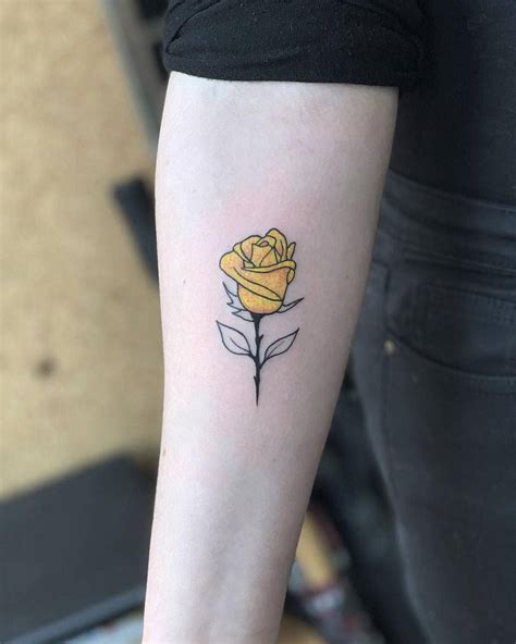 a small yellow rose tattoo on the arm
