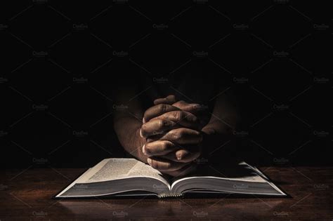 man sitting alone in a dark room with praying hands