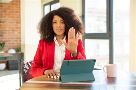 pretty afro black woman looking serious showing open palm …